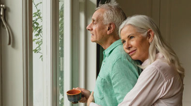 Senior couple hugging looking out a series of windows.